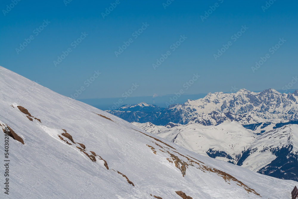 View of the snow-capped mountains in the Schmitten ski area in Zell am See. In the background is a beautiful sky with clouds.