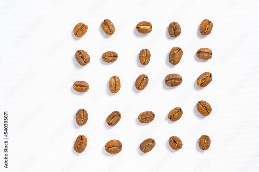 Coffee beans are laid out in a row on a white background. Coffee beans are laid out in a row on a white background.