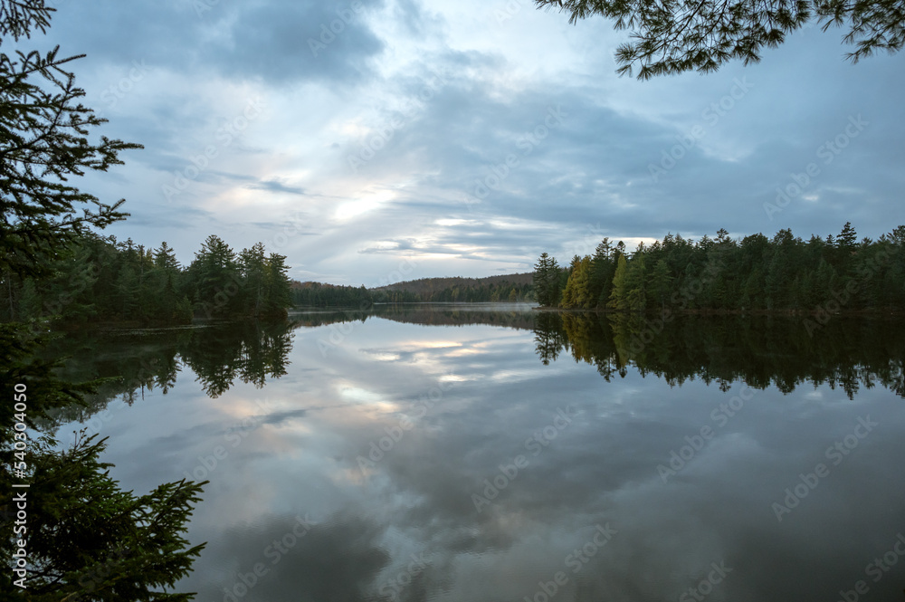 Clouds reflecting on a calm, tree lined lake. Maple Leaf Lake, Algonquin Provincial Park, Ontario, Canada. Clouds reflecting on a calm, tree lined lake. Maple Leaf Lake, Algonquin Provincial Park, Ontario, Canada.