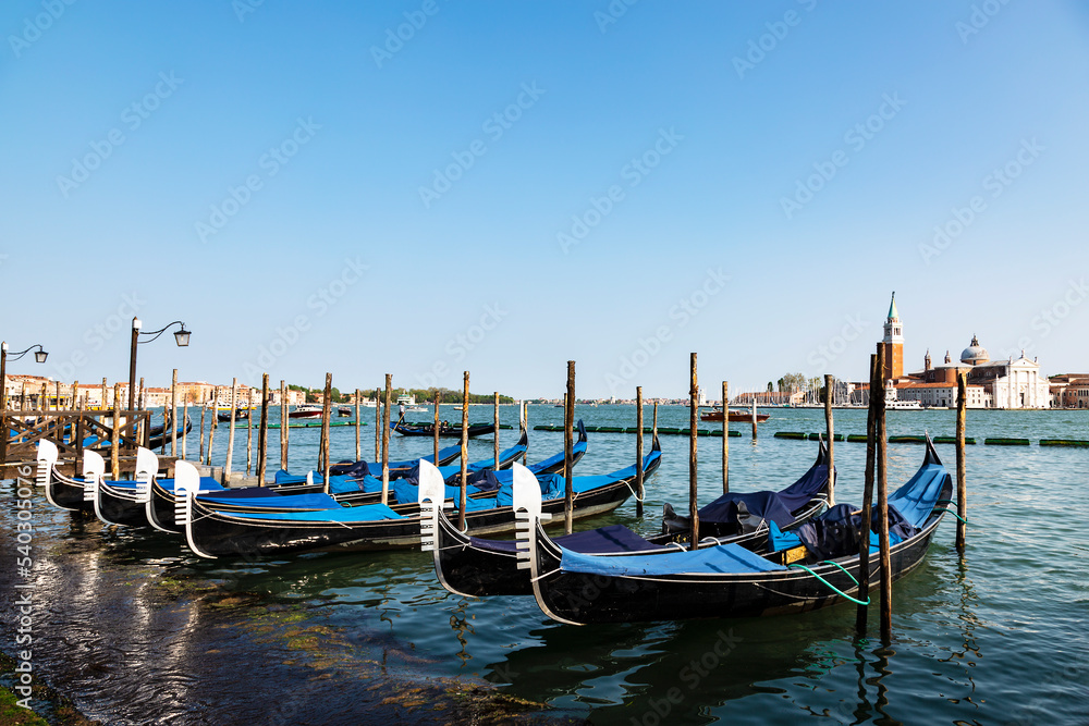 Gondolas at the pier of the Venetian Lagoon overlooking the Cathedral of San Giorgio Maggiore. Venice, Italy