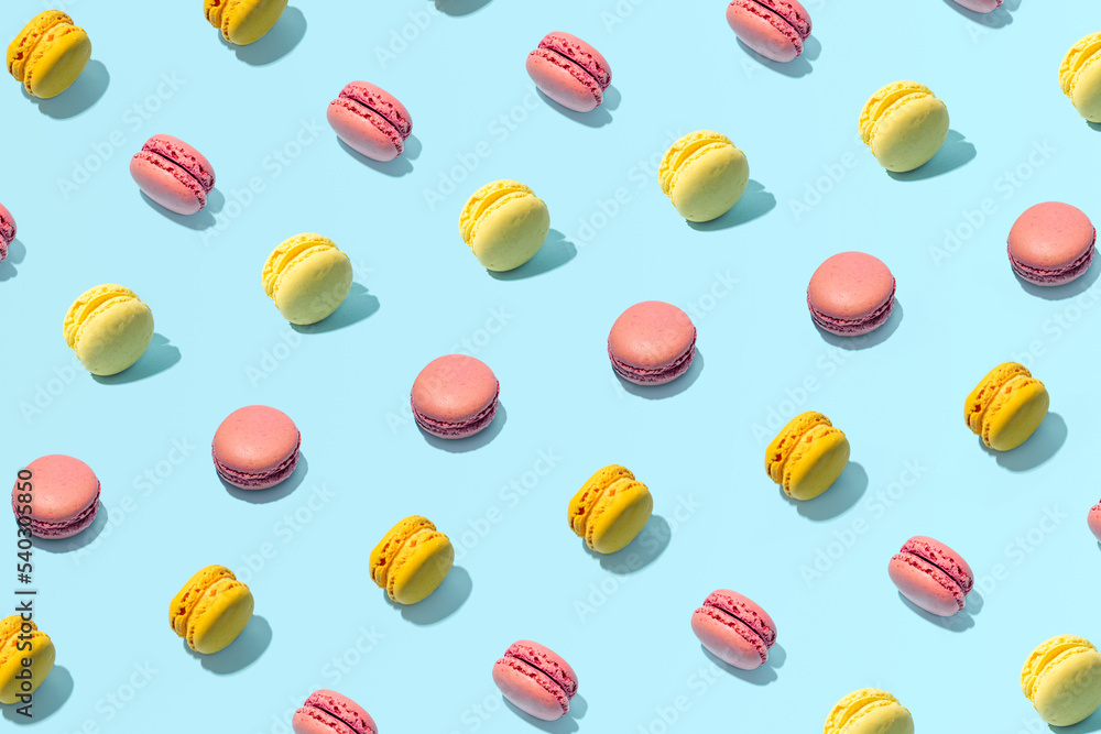 Macarons, traditional French cookies, colorful food pattern on a pastel blue background. Macarons, traditional French cookies, colorful food pattern on a pastel blue background.