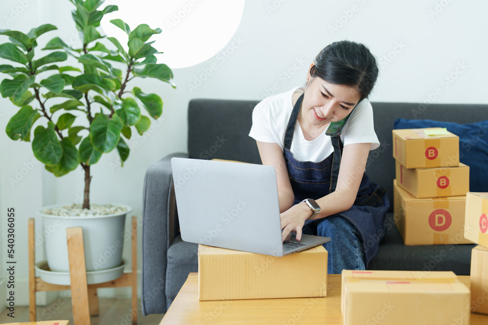 Starting small business entrepreneur of independent Asian woman smiling using laptop computer with cheerful success of online marketing package box items and SME delivery concept Starting small business entrepreneur of independent Asian woman smiling using laptop computer with cheerful success of online marketing package box items and SME delivery concept