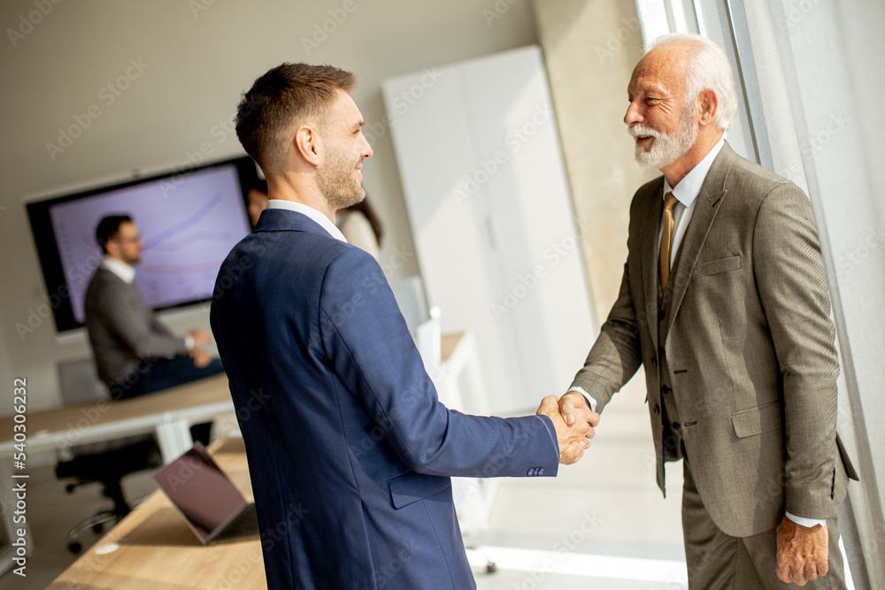Senior business man handshaking with his young colleague Senior business man handshaking with his young colleague
