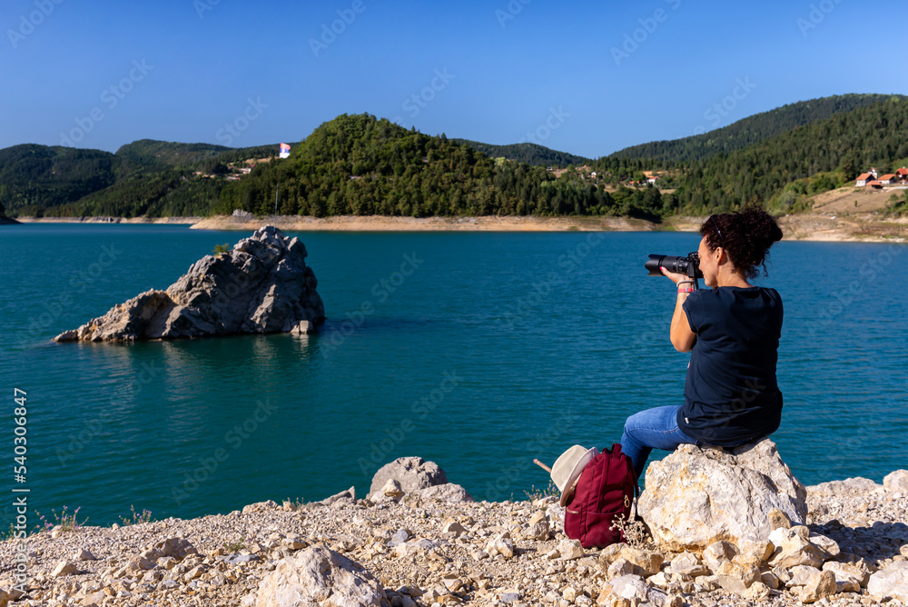 Woman photographer taking photos of a beautiful lake