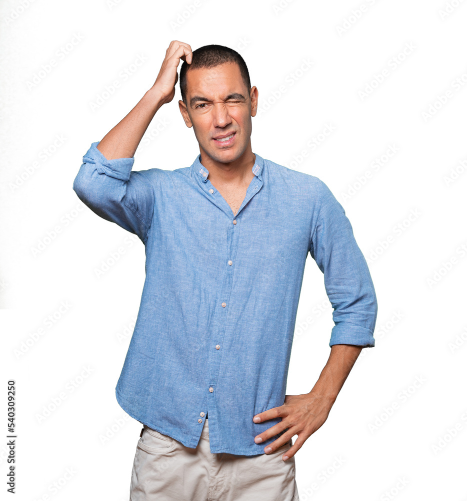 Concerned young man making a scratching gesture Concerned young man making a scratching gesture