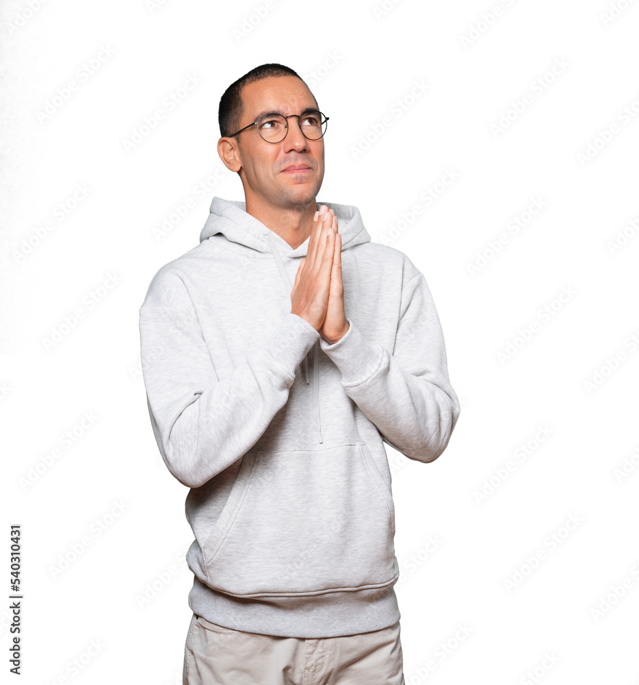 Concerned young man praying gesture Concerned young man praying gesture