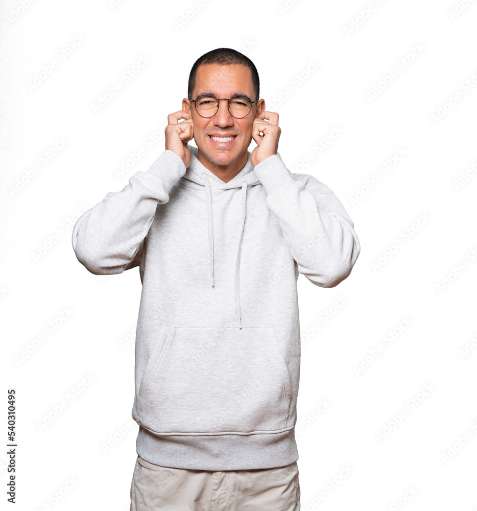 Fototapeta premium Young man worried about loud noises and covering his ears