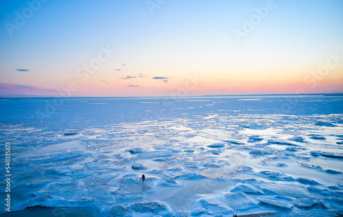 Print op canvas Aerial view - lonely man walk on ice on sunset over a frozen sea