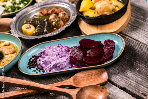 Eid Mubarak Traditional Ramadan Iftar dinner. Assorted tasty food in authentic rustic dishes on wooden blue background. Turkish Bosnian food meat kebab, pita, Sarma, klepe, sogan dolma. photo