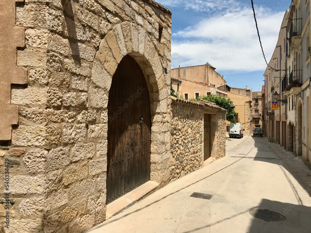 Montblanc, Spain, June 2019 - A stone building that has a sign on a brick sidewalk