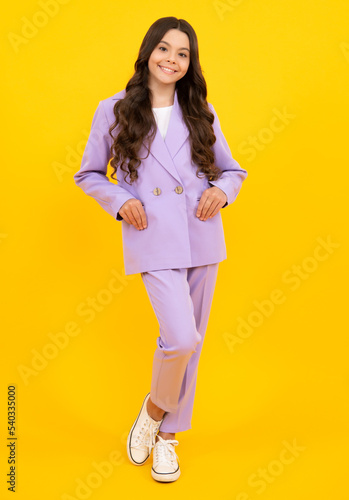 Full length of attractive cheerful teenager child girl in casual fashion clothes over yellow isolated background. Fashion kids suit. Happy teenager, positive and smiling emotions of teen girl.