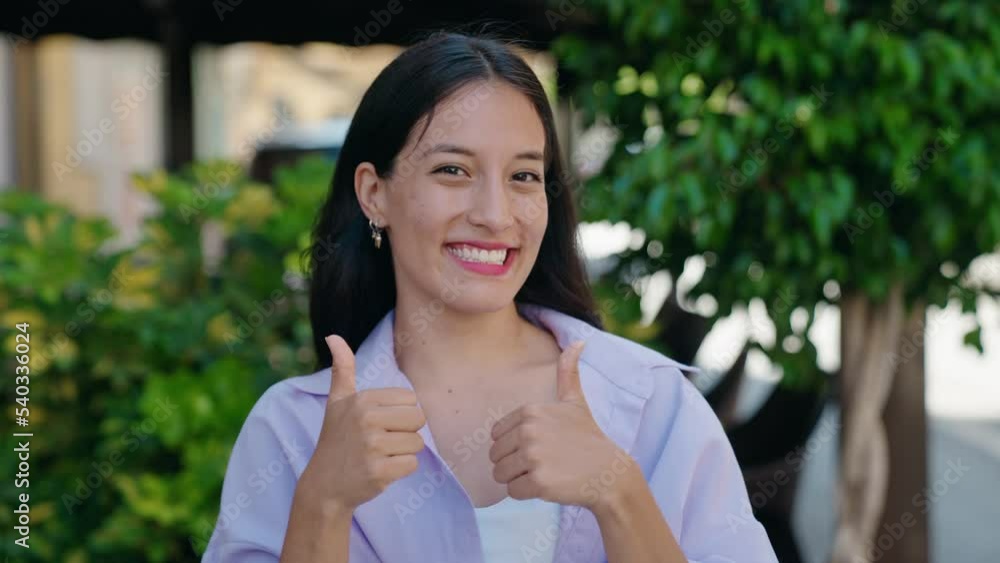 Young beautiful hispanic woman smiling confident doing ok sign with thumbs up at street Young beautiful hispanic woman smiling confident doing ok sign with thumbs up at street