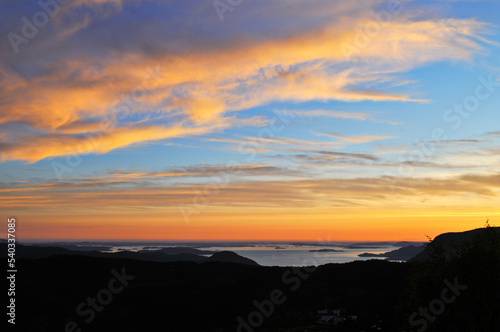 Sunset, irradiated orange clouds over the sea and mountains in Preikestolen park, Norway