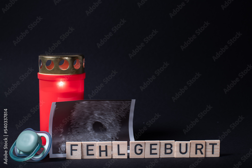 Buchstaben mit dem Wort Fehlgeburt mit Kerze, Ultraschallbild und
