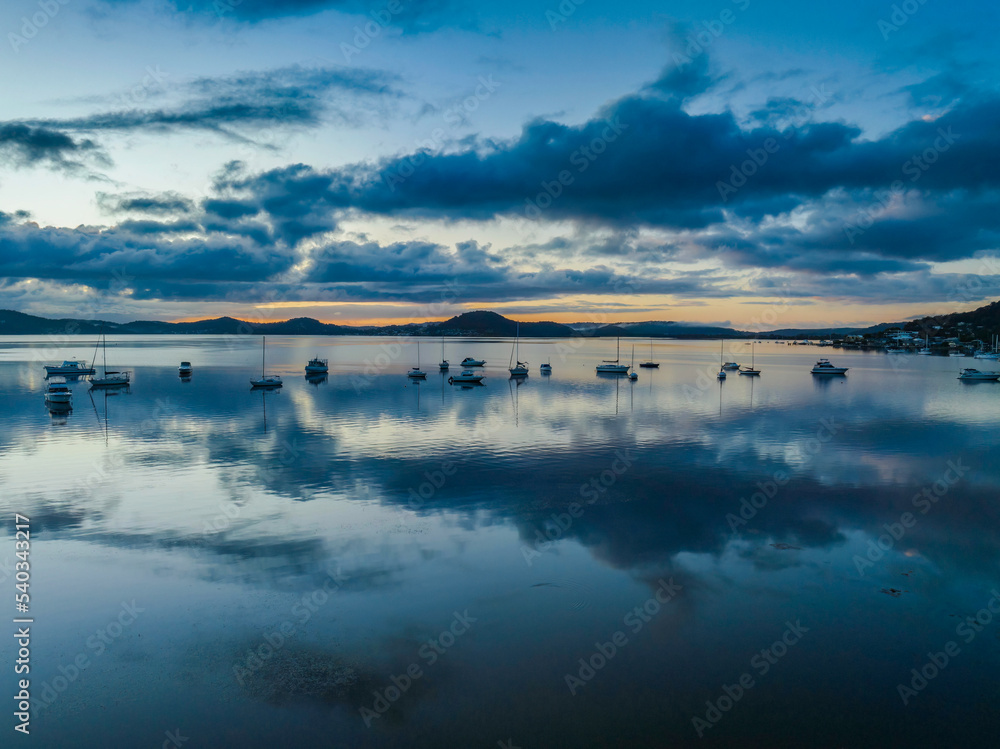 Aerial sunrise waterscape with boats, rain clouds and reflections