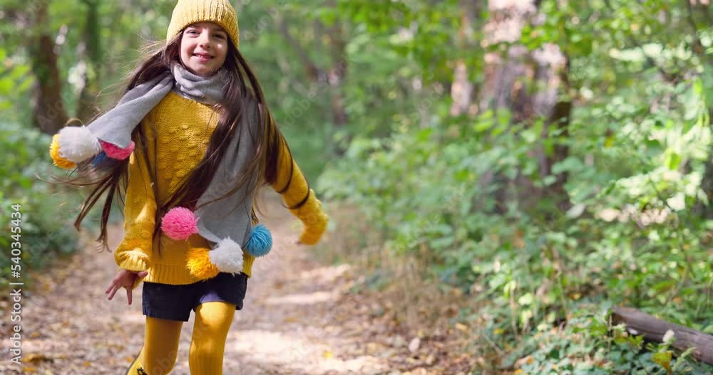 Happy girl walks on forest trail on a sunny autumn day. Carefree kid run in a park pathway Happy girl walks on forest trail on a sunny autumn day. Carefree kid run in a park pathway