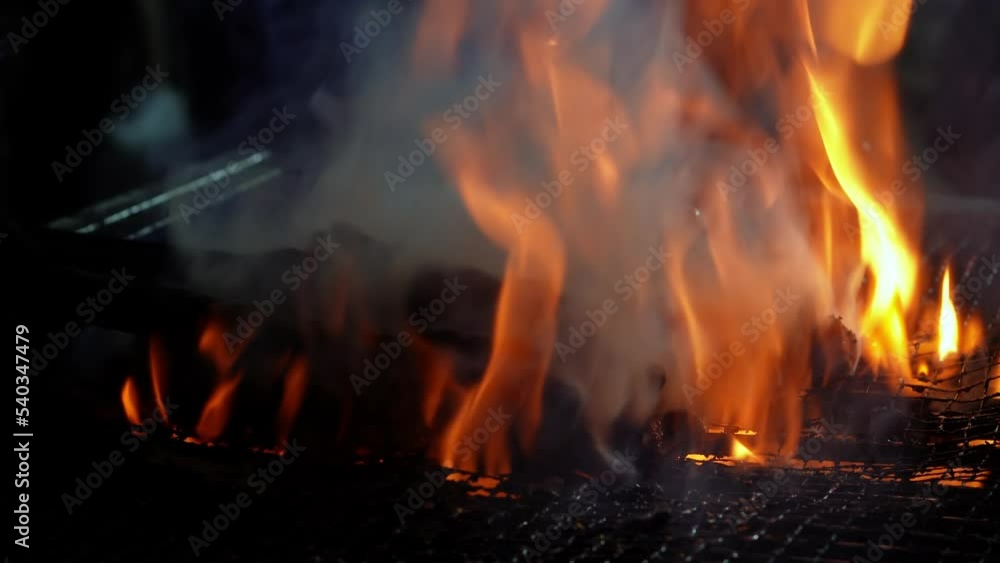 Close up the meat is cook on the steel grilled with fire flame release smoke Close up the meat is cook on the steel grilled with fire flame release smoke