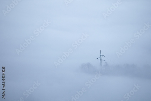 Fotografie Power line in mountain vallery with fog