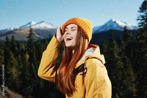Woman smile with teeth hiker portrait in yellow raincoat travel in the fall and hiking in the mountains in the sunset sunshine freedom