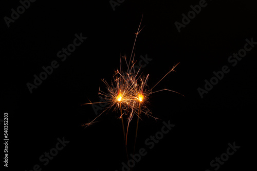 Two burning sparkler sticks on black background