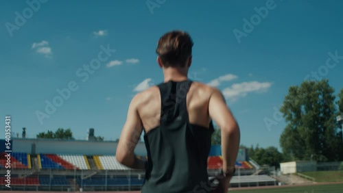 A professional athlete runs through an empty stadium on a bright summer day. Handheld camera