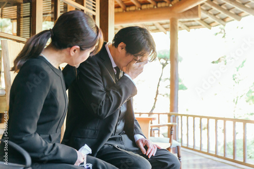 お葬式で泣く喪服を着た遺族の日本人男女
 photo