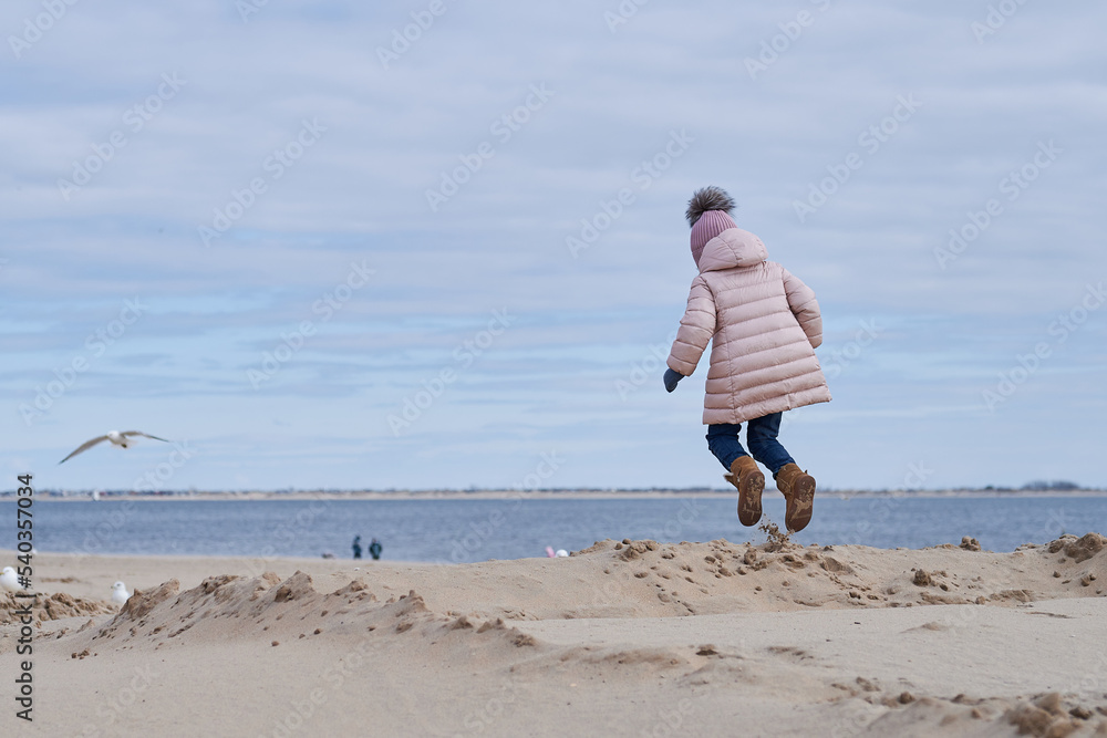 Cute girl fooling around at the beach in a winter coat