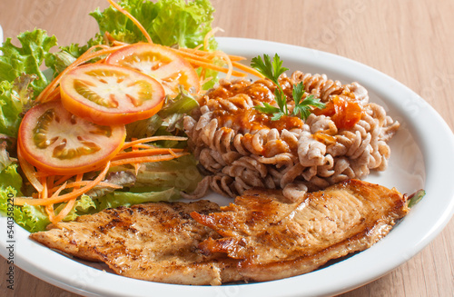 delicioso prato saudável com carne de frango e salada de alface e tomate e macarrão integral de fuso photo