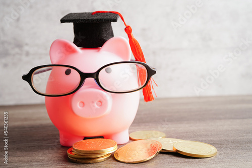 Pigging bank wearing eyeglass with coins and calculator saving bank education concept. photo