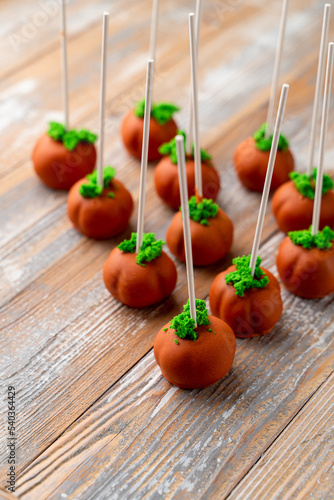 Halloween ideas, pumpkin cake pops on a wooden table soft light studio shot