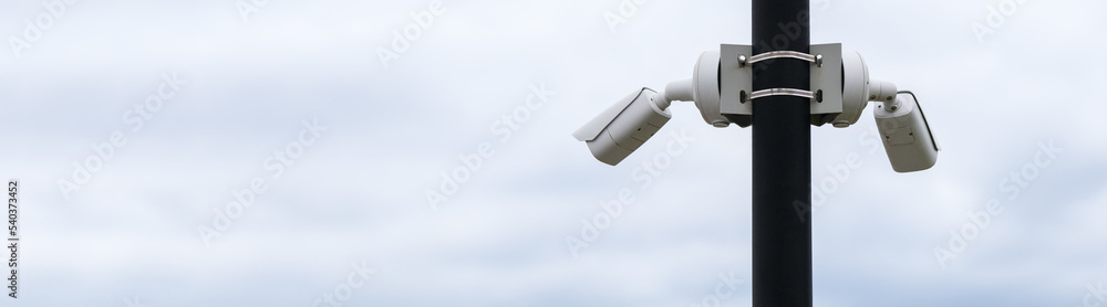 Outdoor security camera on a pole against the sky. Horizontal photo. Banner