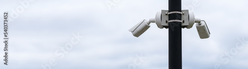 Outdoor security camera on a pole against the sky. Horizontal photo. Banner