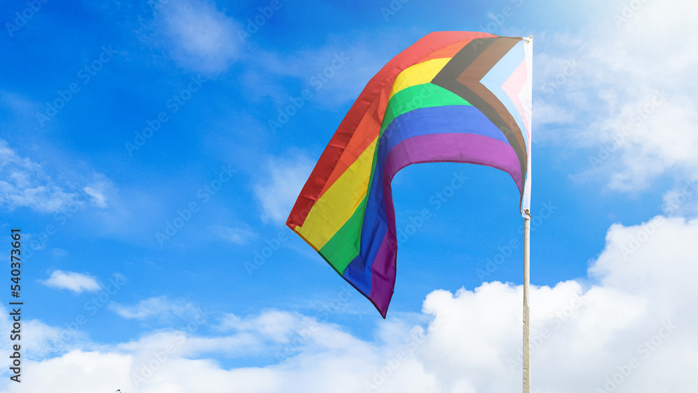 LGBT rainbow flag waving with blue sky in background to enhance LGBTQ+ community around the world LGBT rainbow flag waving with blue sky in background to enhance LGBTQ+ community around the world