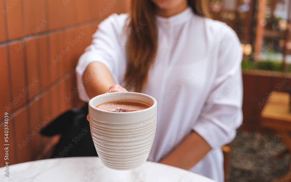 Closeup image of a woman holding and serving a cup of hot chocolate Closeup image of a woman holding and serving a cup of hot chocolate