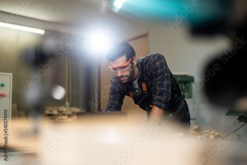 Carpenter men with bearded wearing glasses and working in wood workshop