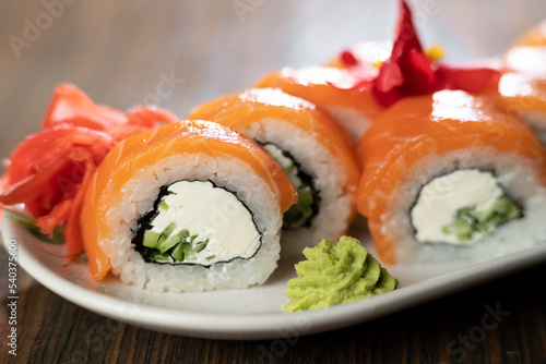 Sushi roll Philadelphia with salmon and cream cheese on a plate with ginger and wasabi. Sushi menu. Japanese food