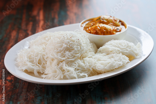 Photography Noolappam Idiyappam rice noodles a popular traditional steam cooked Kerala breakfast dish with hot and spicy egg roast curry on a houseboat Alleppey India