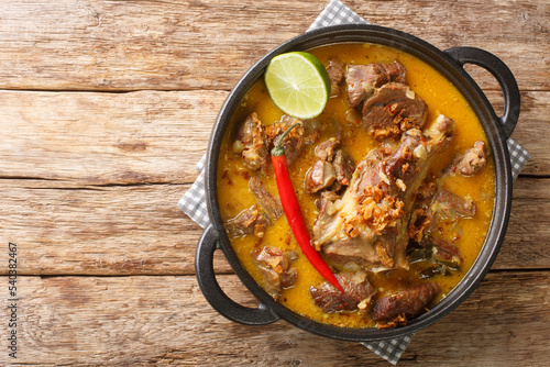 Indonesian food gulai kambing goat curry spicy stew closeup on the pan on the wooden table. Horizontal top view from above photo