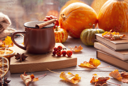 Autumn mood, autumn atmosphere. A cup of coffee, pumpkins, knitted warm blankets, books, autumn leaves on the windowsill.