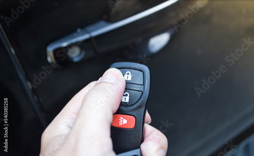 Close up hand of man holding and push car remote control for lock and Un-lock old black car ,Car key and  remote.