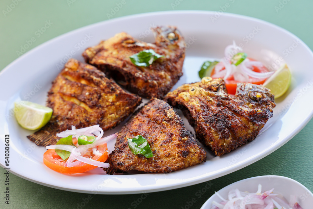 Kerala fish fry Karimeen Pollichathu a popular hot and spicy baked fish in banana leaves Alleppey India. fried pearl spot fish is marinated with Indian spices then grilled or fried in coconut oil.