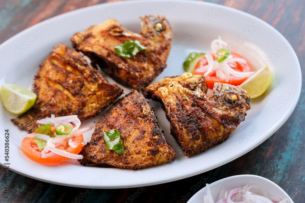 Kerala fish fry Karimeen Pollichathu a popular hot and spicy baked fish in banana leaves Alleppey India. fried pearl spot fish is marinated with Indian spices then grilled or fried in coconut oil.