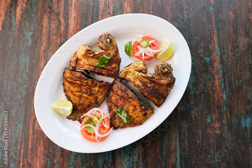 Kerala fish fry Karimeen Pollichathu a popular hot and spicy baked fish in banana leaves Alleppey India. fried pearl spot fish is marinated with Indian spices then grilled or fried in coconut oil. photo