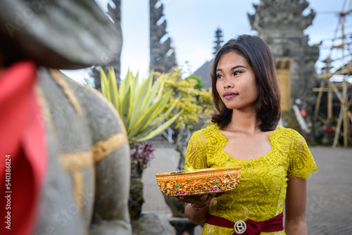 Portrait girl in traditional Balinese yellow and red clothing in hindu temple, Bali. photo