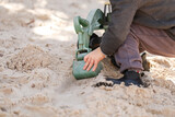 Preschool child playing in sandbox with green digger at kindergarten