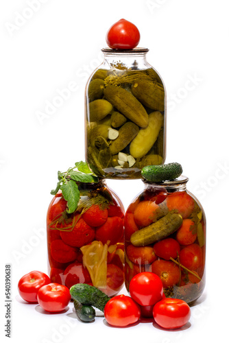 Glass jars with canned tomatoes and cucumbers on a white background