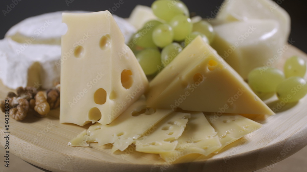 Cheese plate with grapes, honey and nuts rotating on gray background Cheese plate with grapes, honey and nuts rotating on gray background