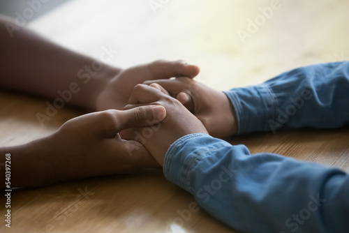 Unknown African girl and guy holding hands, close up. Caring boyfriend touch girlfriend arm during heart-to-heart conversation, declaring of love, teenagers at romantic date. Support, trustworthy talk