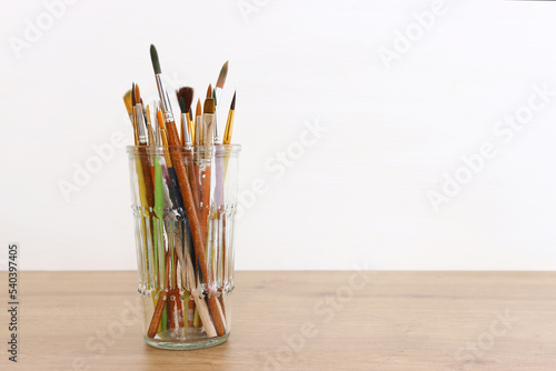 paint brushes in jar over white background. vintage filtered image photo