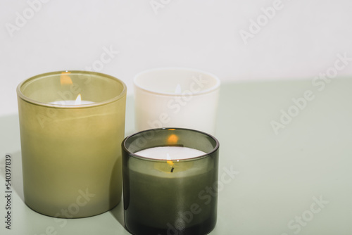 green scented candles burning on a table. sow wax candles with herbal aroma glowing in room. aromatherapy, cosy home, grass fragrance for house.